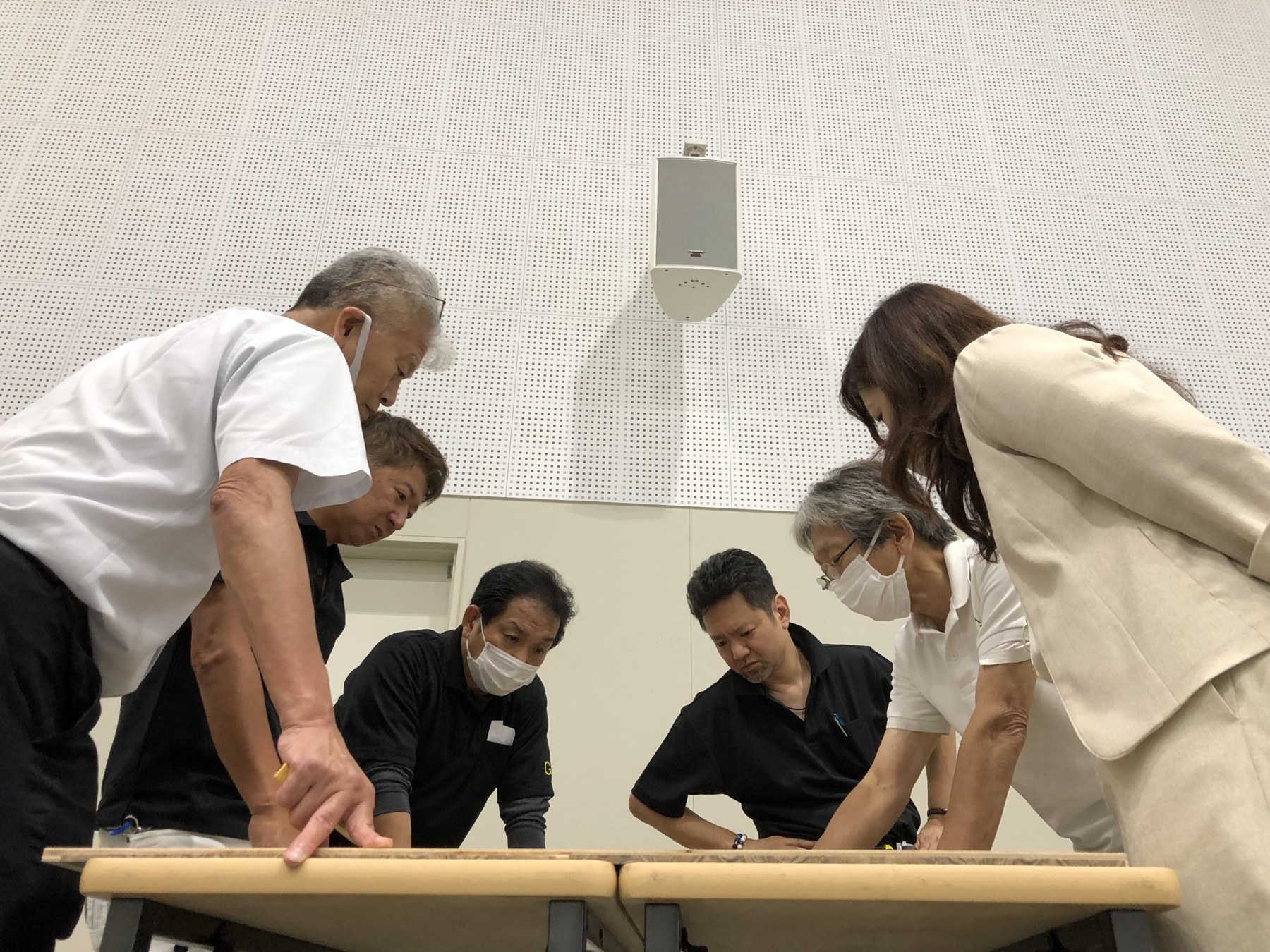 机を囲み、作業を見つめる参加者たち